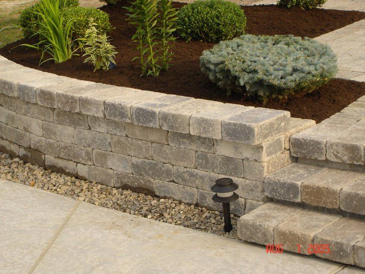 a brick wall surrounds a garden with plants and steps
