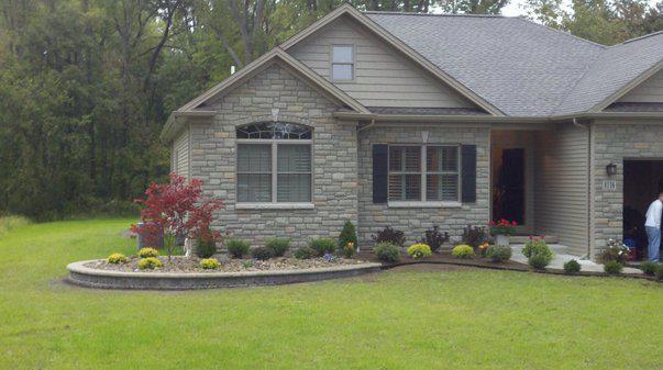 a large stone house with a lush green lawn in front of it .