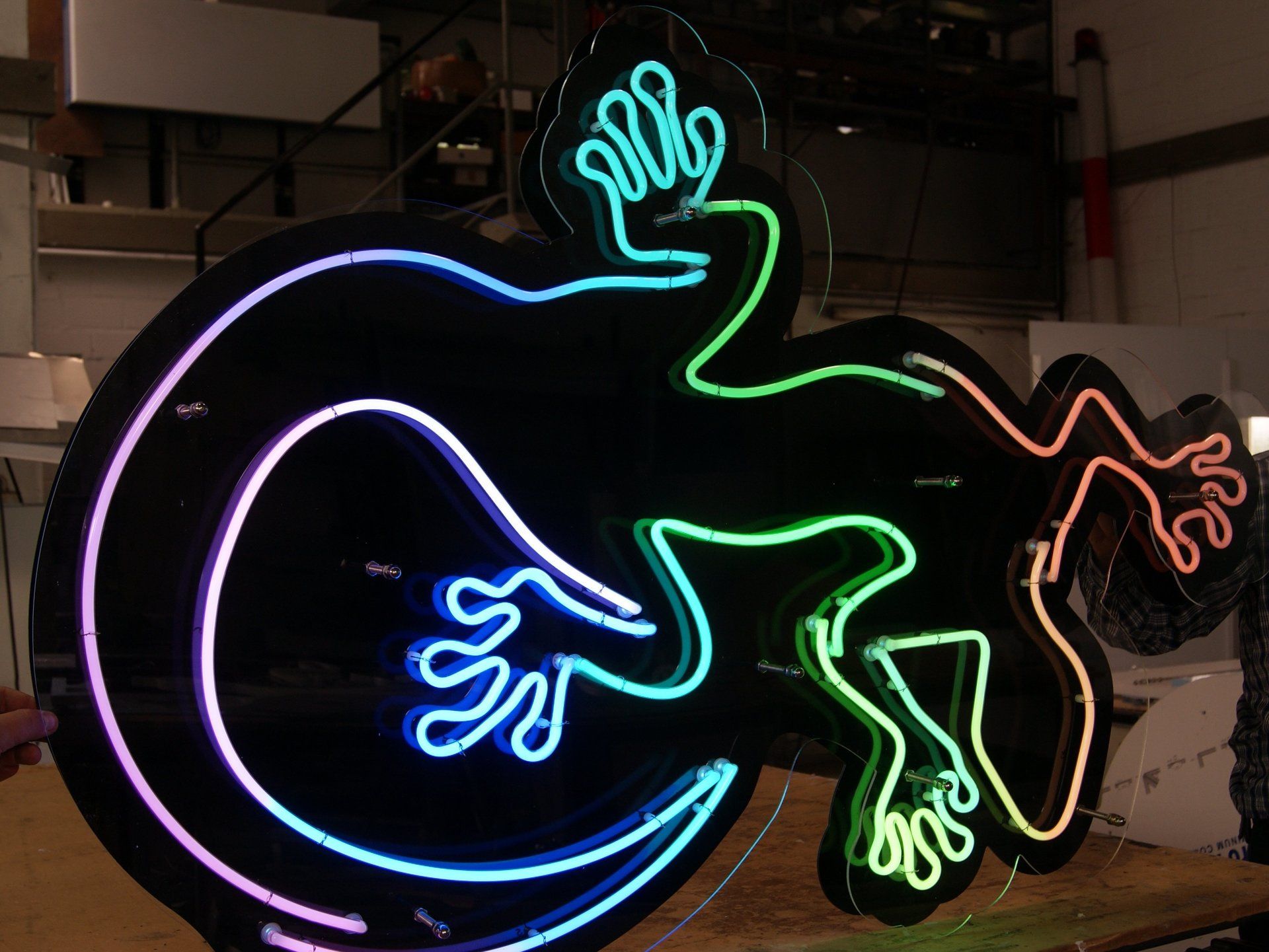 Neon-Gecko-Schild in Blau-, Grün- und Orangetönen.