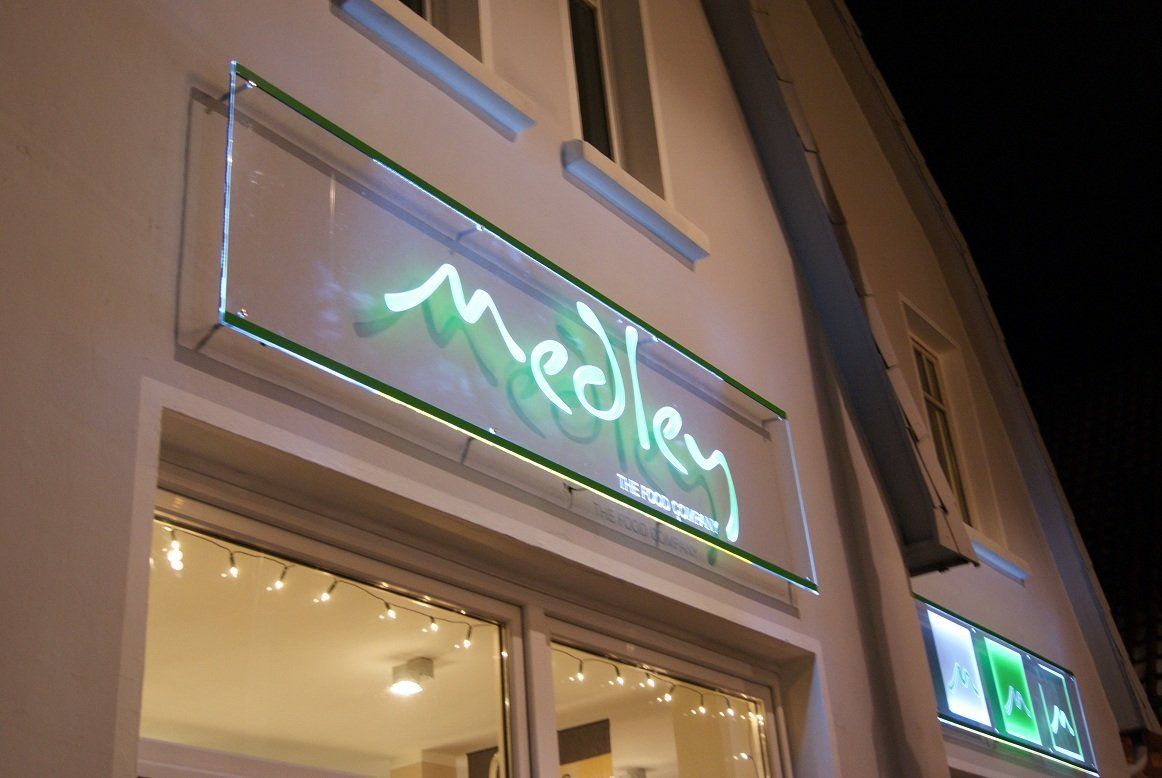 Neongrünes „Medley“-Schild über einem Laden bei Nacht.