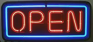 Neonschild mit dem Wort „OPEN“ in Rot auf dunklem Hintergrund, eingerahmt von einem blauen Rand.