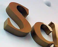 Goldene „SC“-Buchstaben an einer weißen Wand.