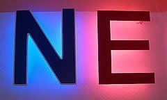 Blaue „N“- und rote „E“-Leuchtschilder an einer weißen Wand.