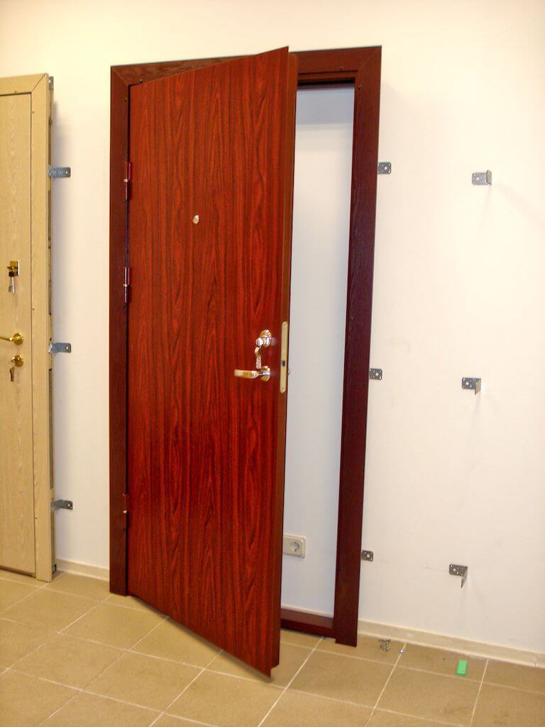 Open, reddish-brown door in a brown doorframe, white wall, brown tiled floor.