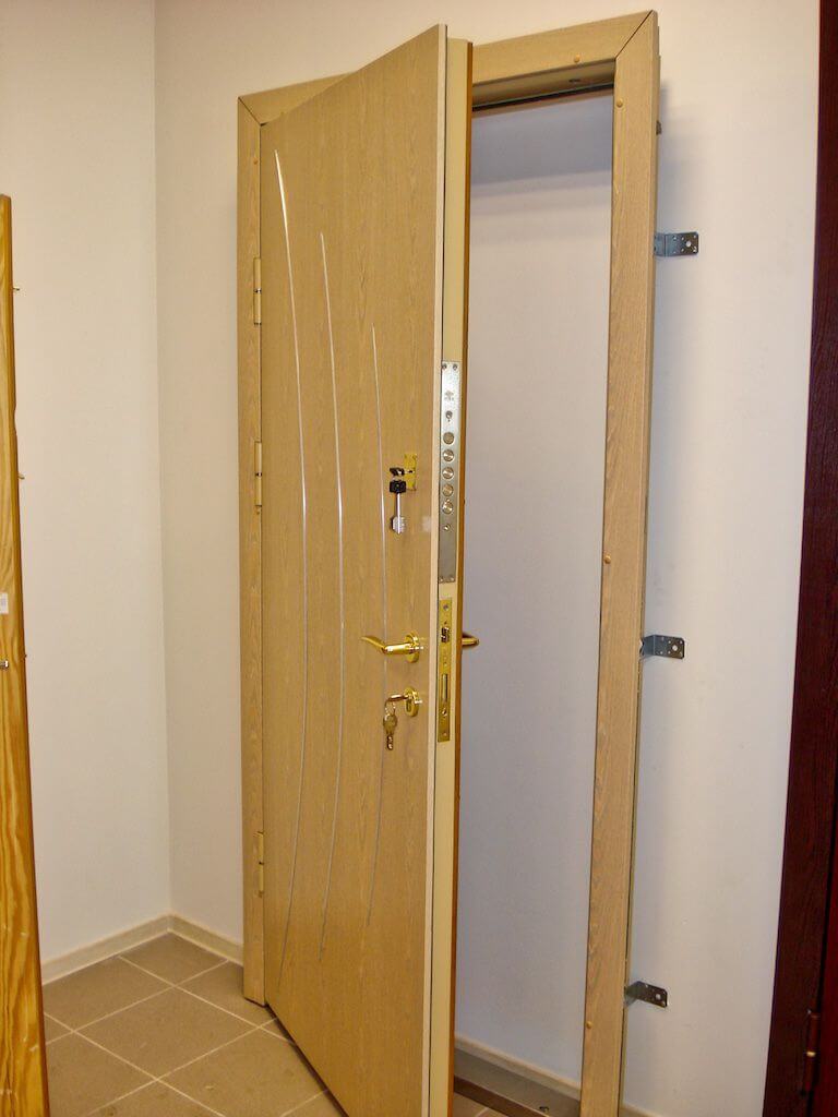 Open beige door in a neutral-toned hallway with a tiled floor.