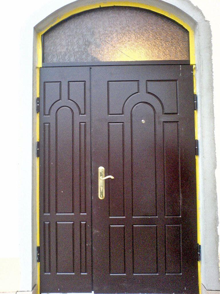 Dark brown double door with arched top and frosted window above; gold handle and yellow trim.
