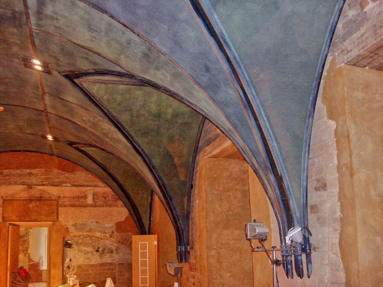 A room with arched ceilings and a lamp on the wall
