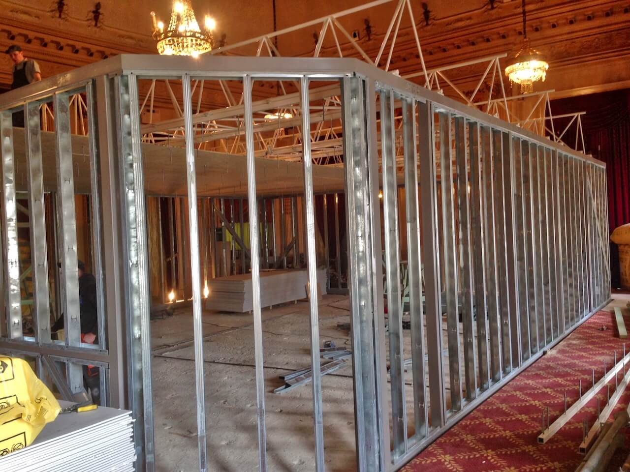 A large metal wall is being built in a room.