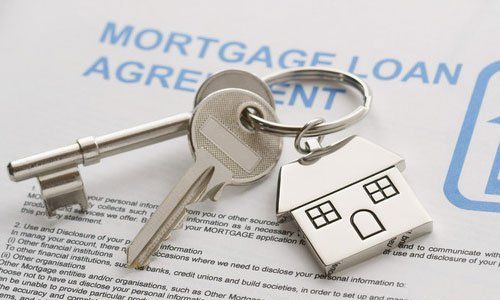 Keys on a mortgage loan agreement with a small house keychain