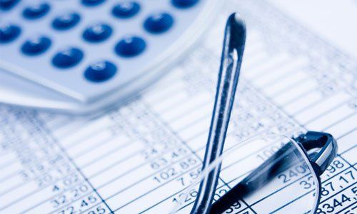 Calculator, pen, and eyeglasses on financial spreadsheets