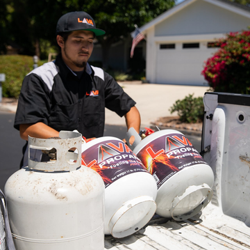 A man is loading propane tanks into a truck