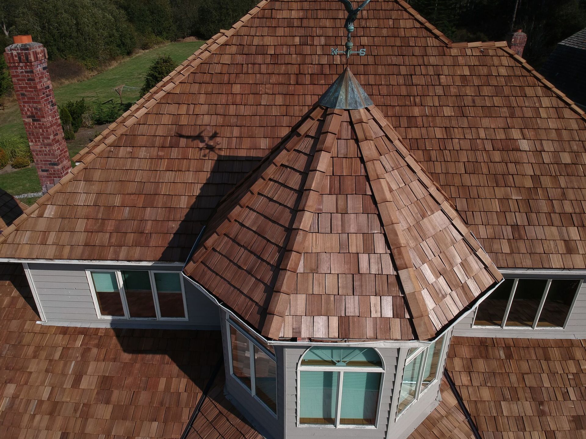 Aerial view of a house roof with a central octagonal turret and brown shingles.