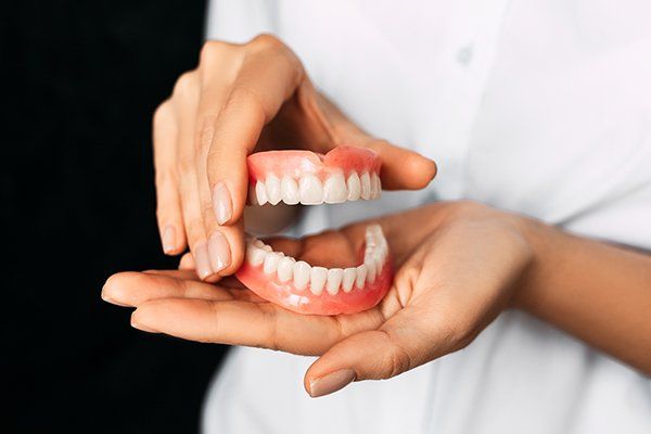 Dentist Holding Dentures — Central PA — Denture Center Dentist Holding Dentures — Central PA — Denture Center