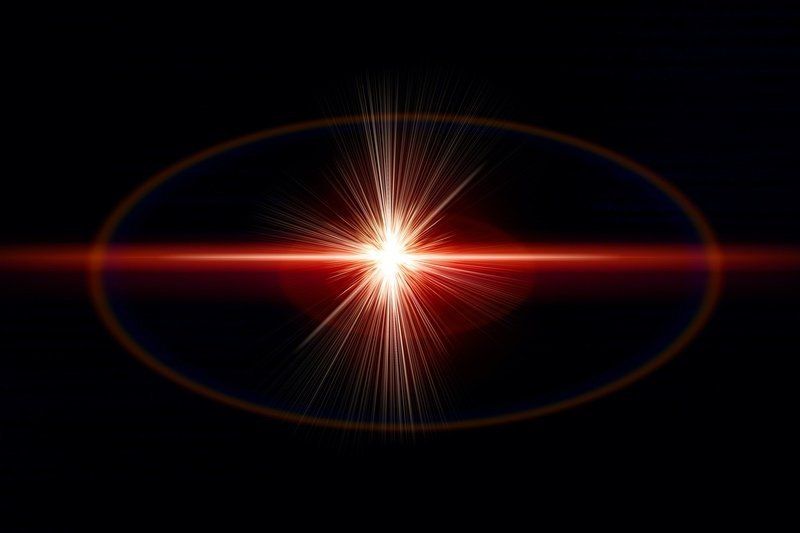 A red light coming out of a lens on a black background.
