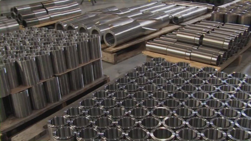 A bunch of metal pipes are stacked on top of each other on pallets.