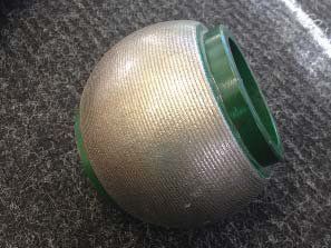 A metal ball with a green rim is sitting on a carpet.