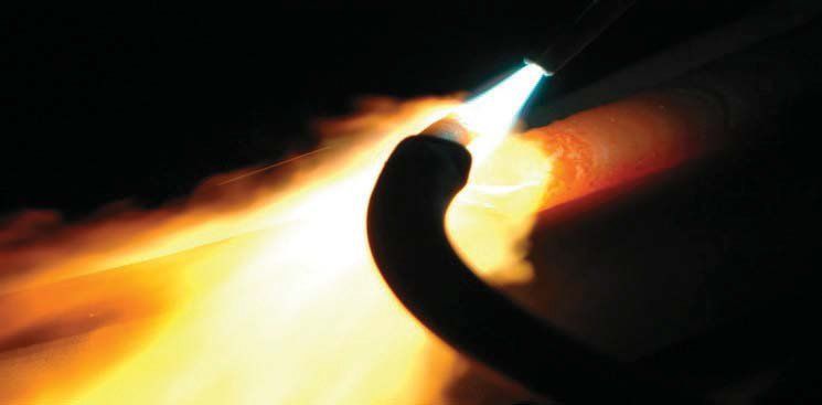 A close up of a spark plug with flames coming out of it.