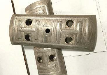 Two metal pieces with holes in them are sitting on top of each other on a table.