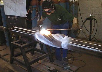 A man is welding a piece of metal in a workshop.