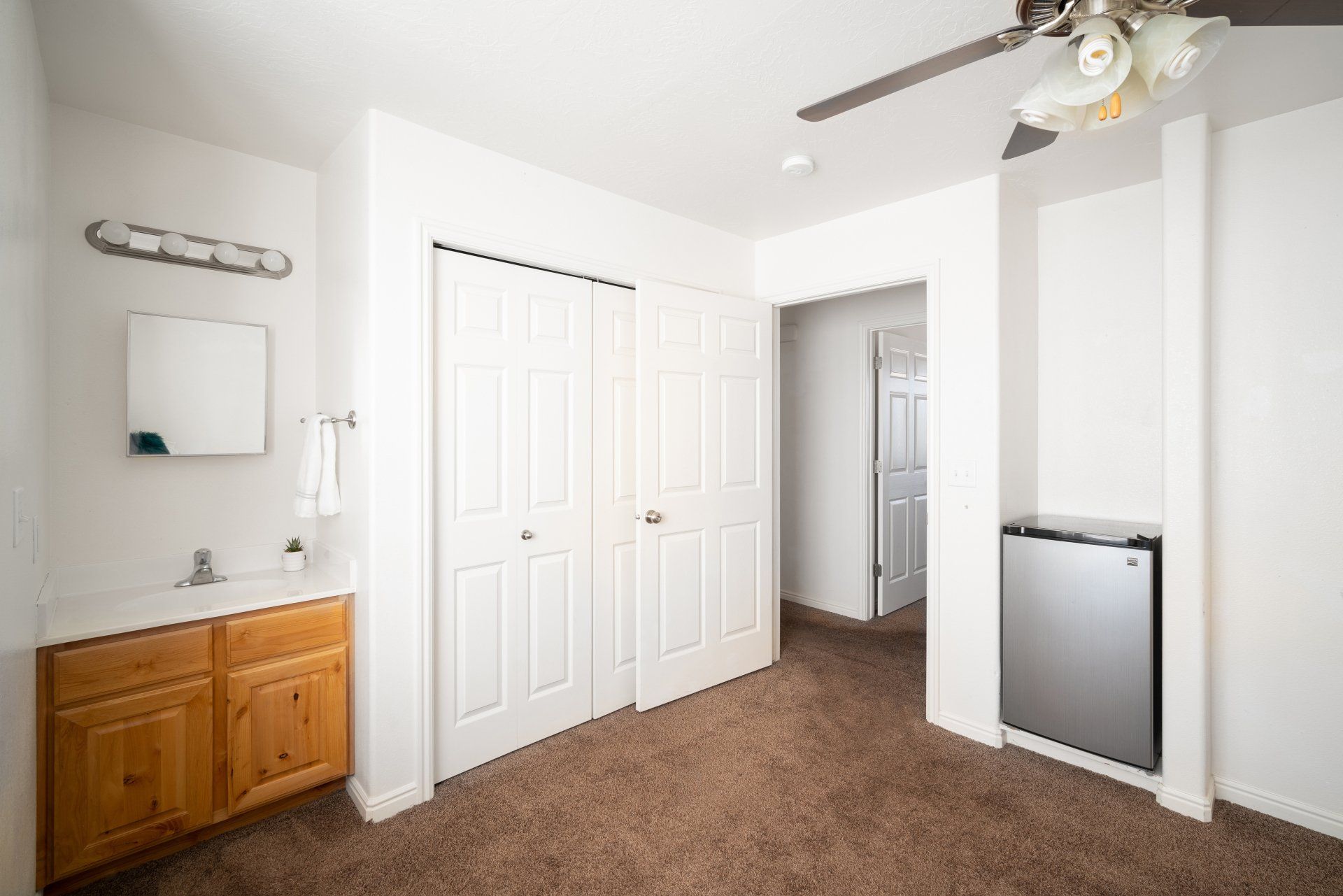 Large furnished private bedroom near Utah Tech University with a bed, vanity sink, desk, closet, and mini fridge.
