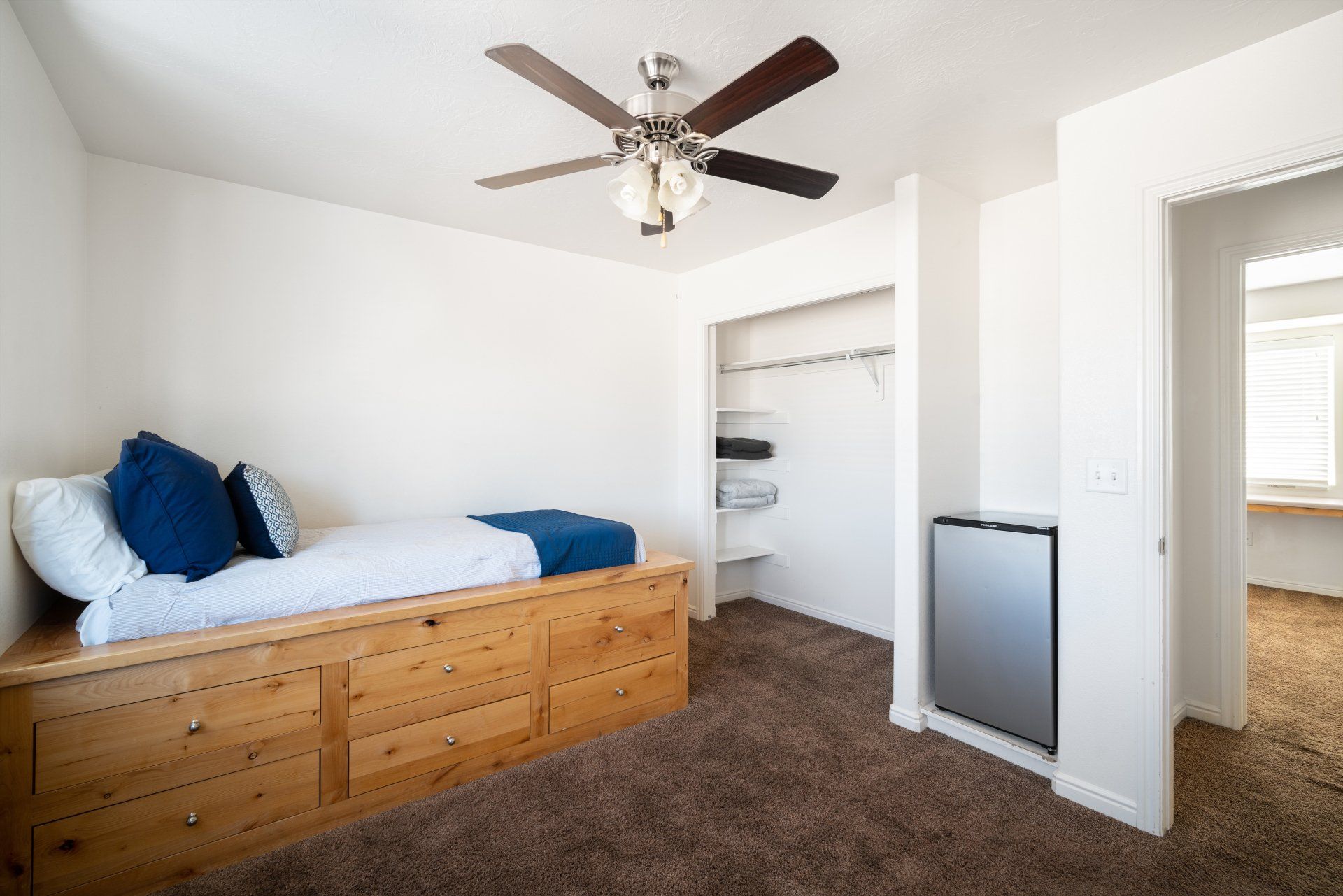 Large furnished private bedroom near Utah Tech University with a bed, vanity sink, desk, closet, and mini fridge.
