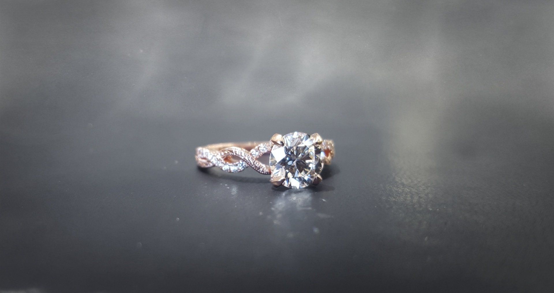 A close up of a diamond ring on a black surface.