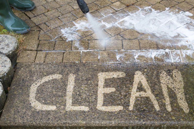 a person is cleaning a brick walkway with a high pressure washer .
