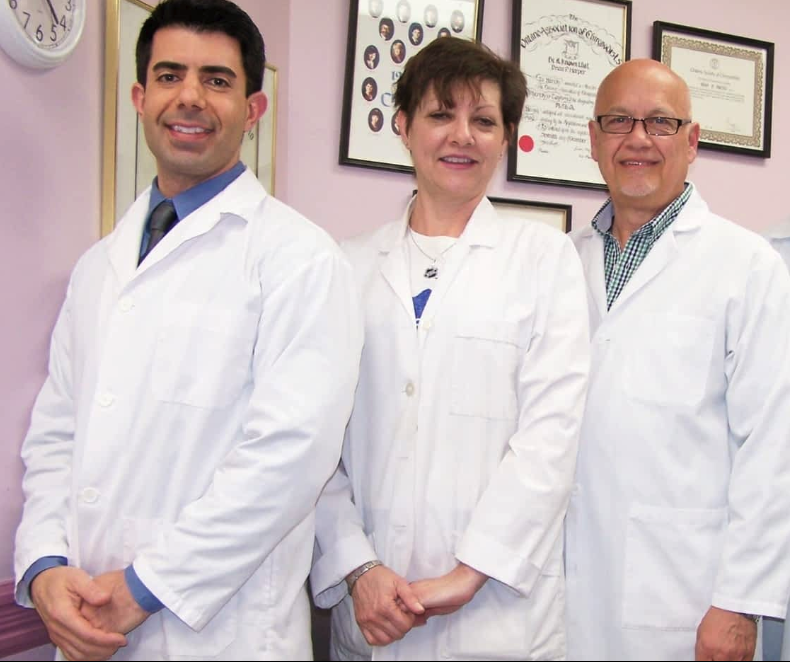 Three doctors are posing for a picture in front of a clock