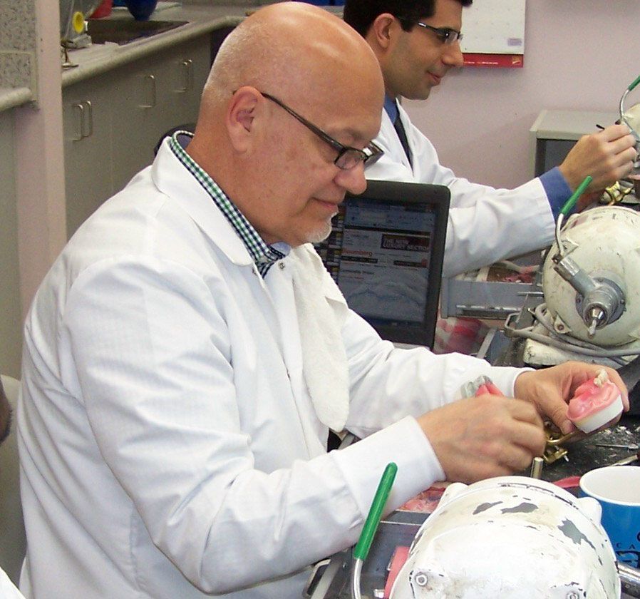 A man in a lab coat is working on a dental model