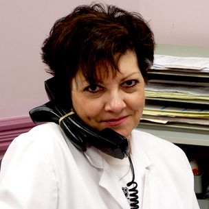 A woman in a lab coat is talking on a phone
