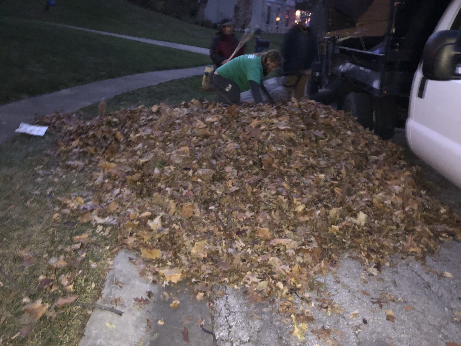 A man is raking leaves in front of a truck.