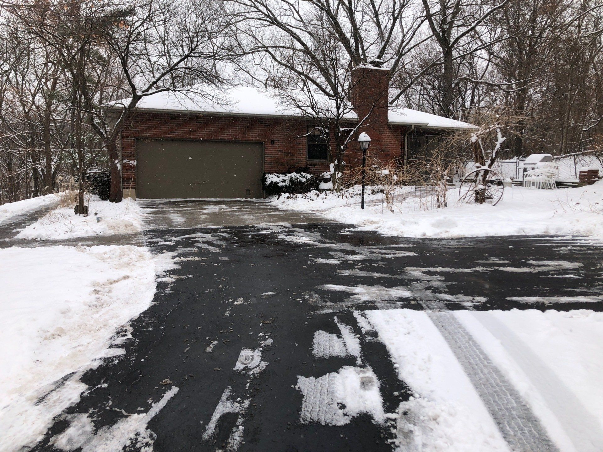 A snowy driveway leading to a brick house