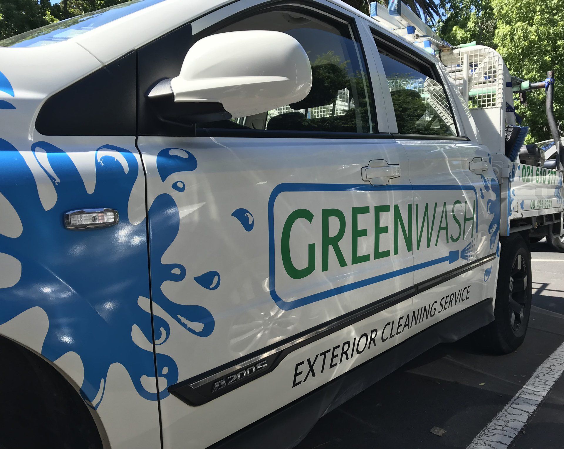 A white car with greenwash exterior cleaning service written on the side