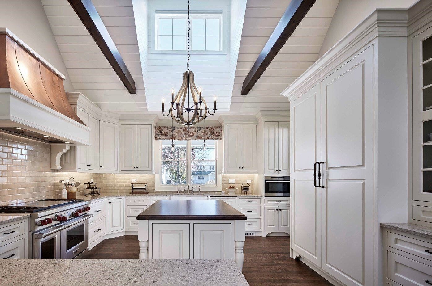 A kitchen with white cabinets , stainless steel appliances , granite counter tops and a large island.