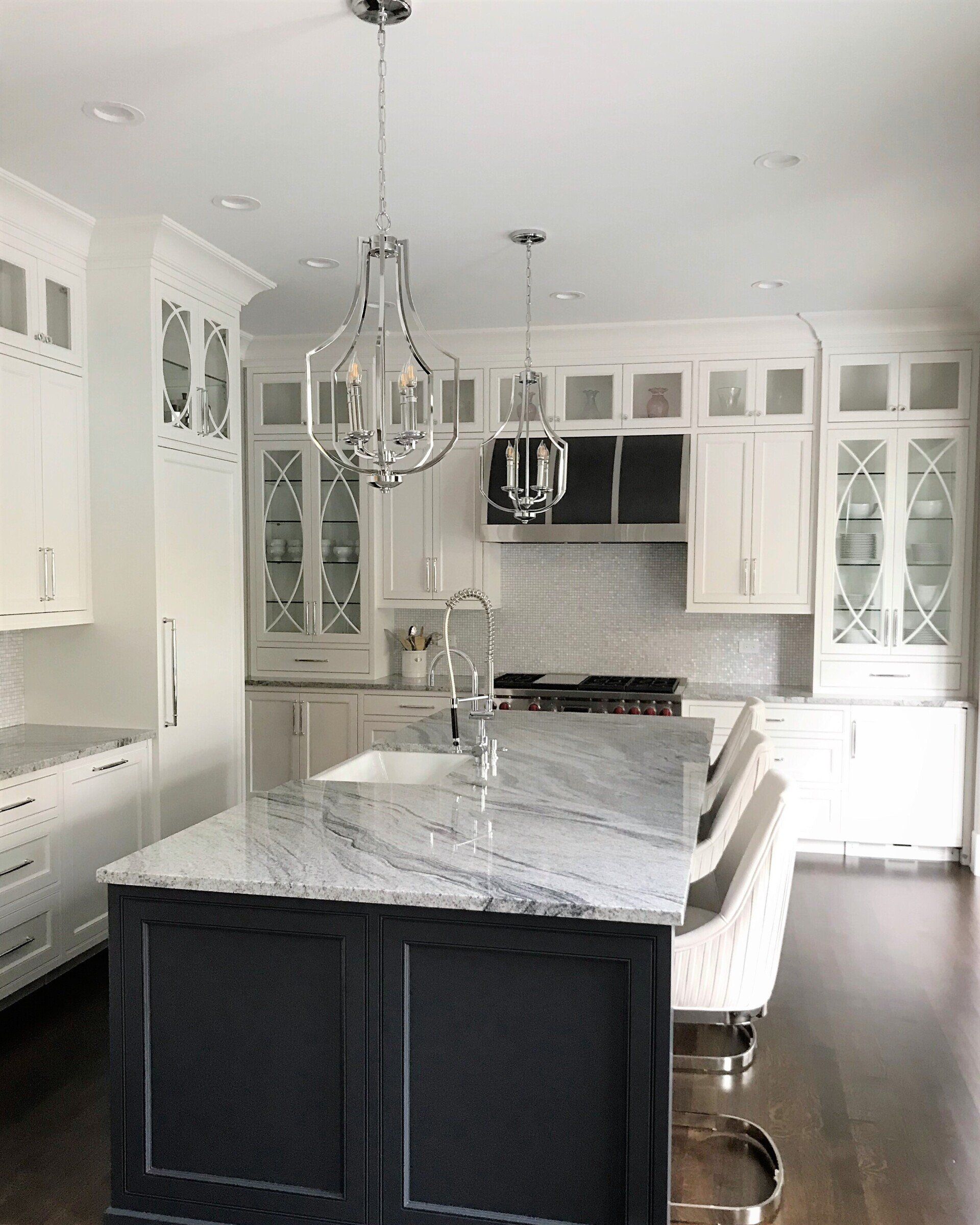 A kitchen with white cabinets and a large island in the middle.
