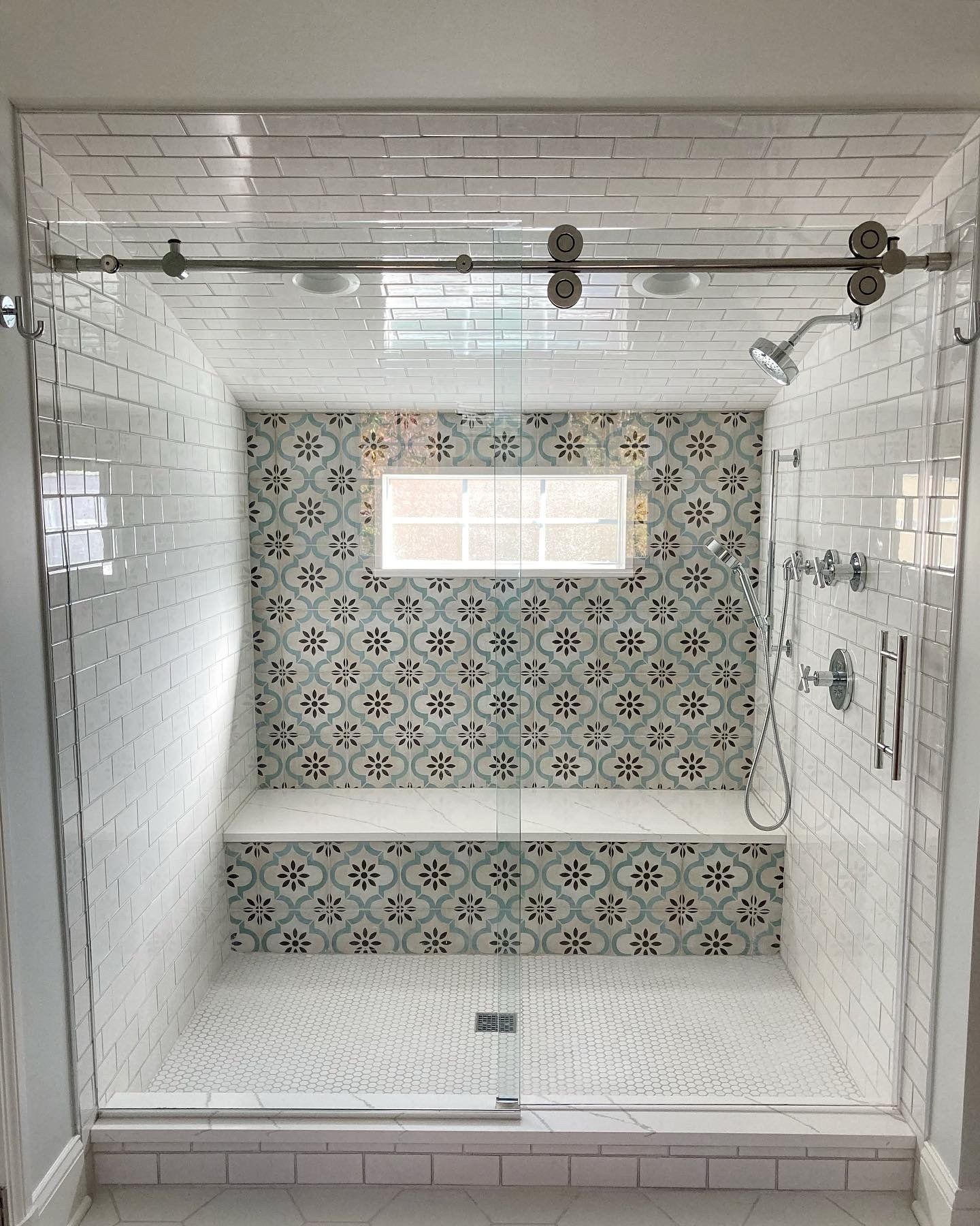 A bathroom with a sliding glass shower door and a bench.