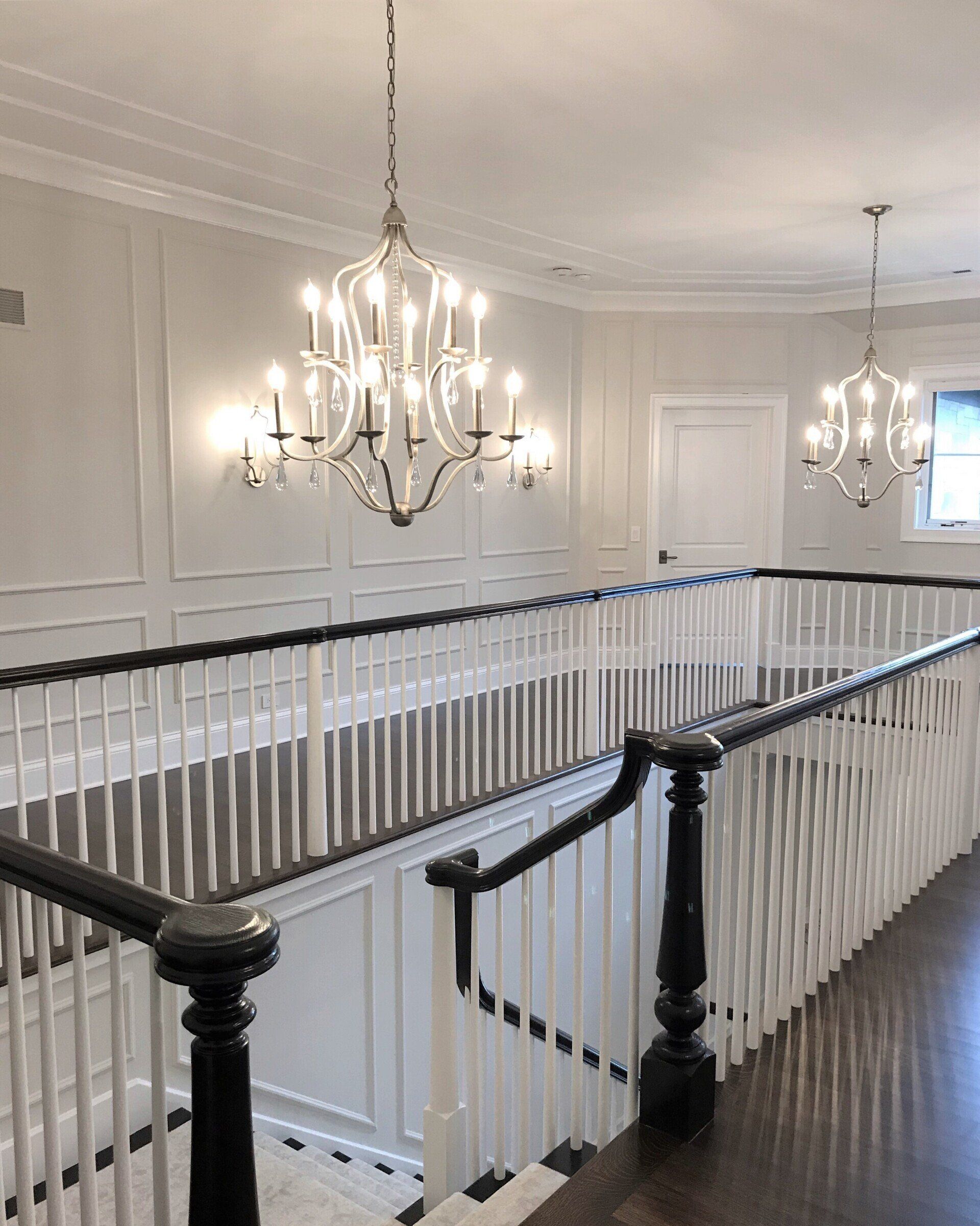 A staircase with a black railing and a chandelier hanging from the ceiling.