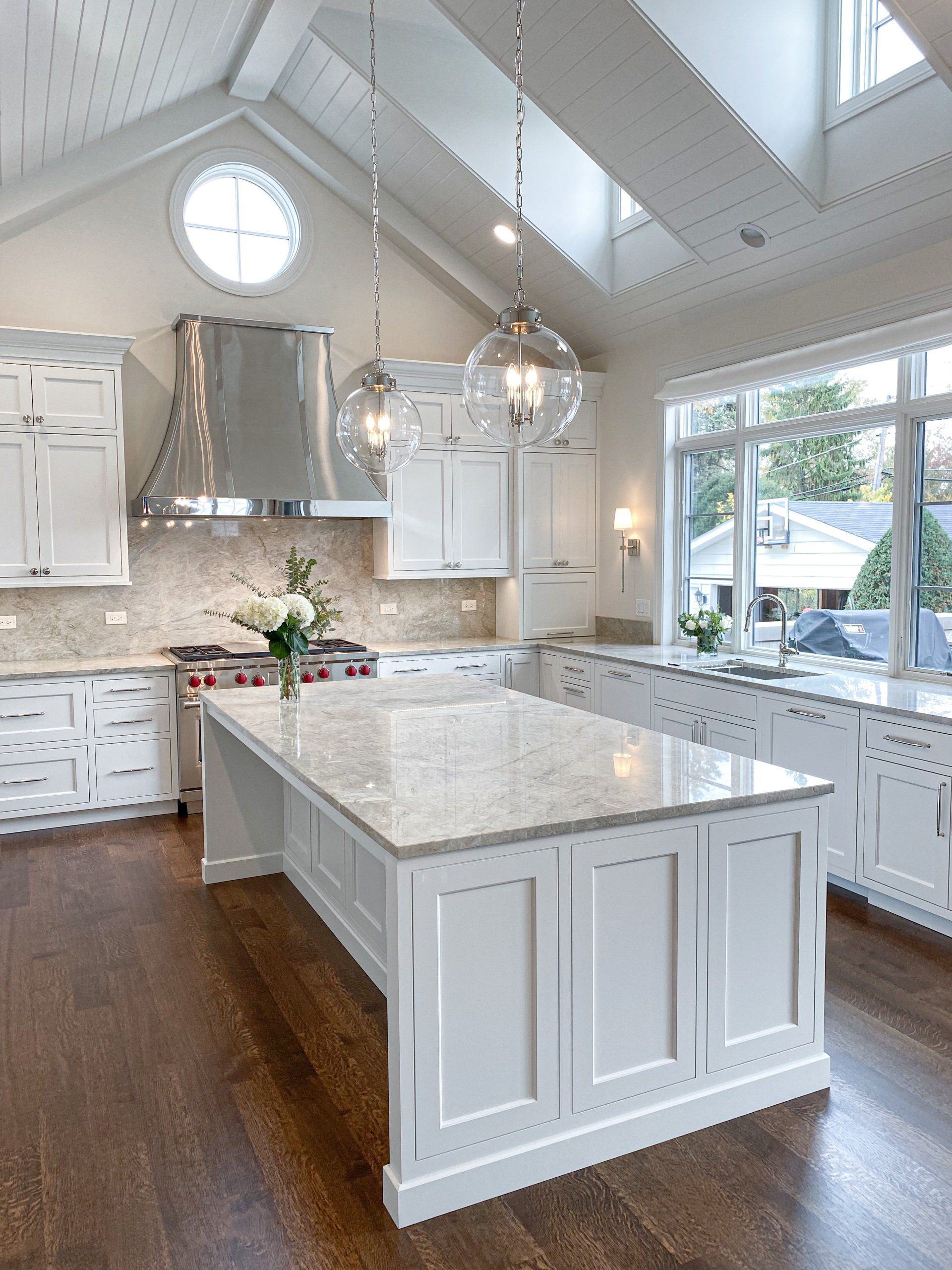 A kitchen with white cabinets and a large island in the middle