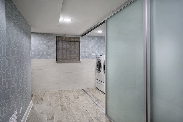 A laundry room with a washer and dryer and a sliding glass door.