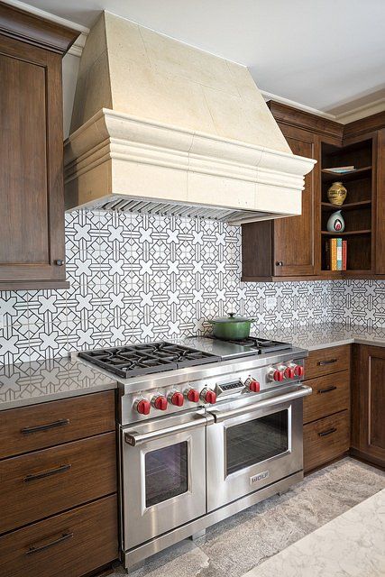 A kitchen with a stove top oven and a hood above it.