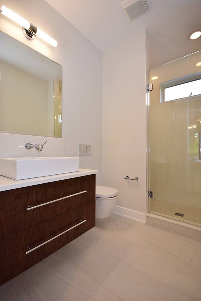 A bathroom with a toilet , sink , mirror and shower.