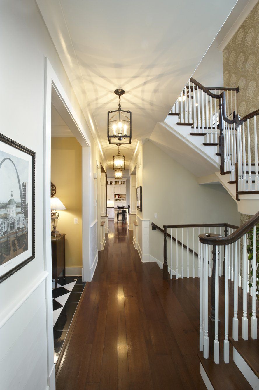 A long hallway with stairs and a picture on the wall