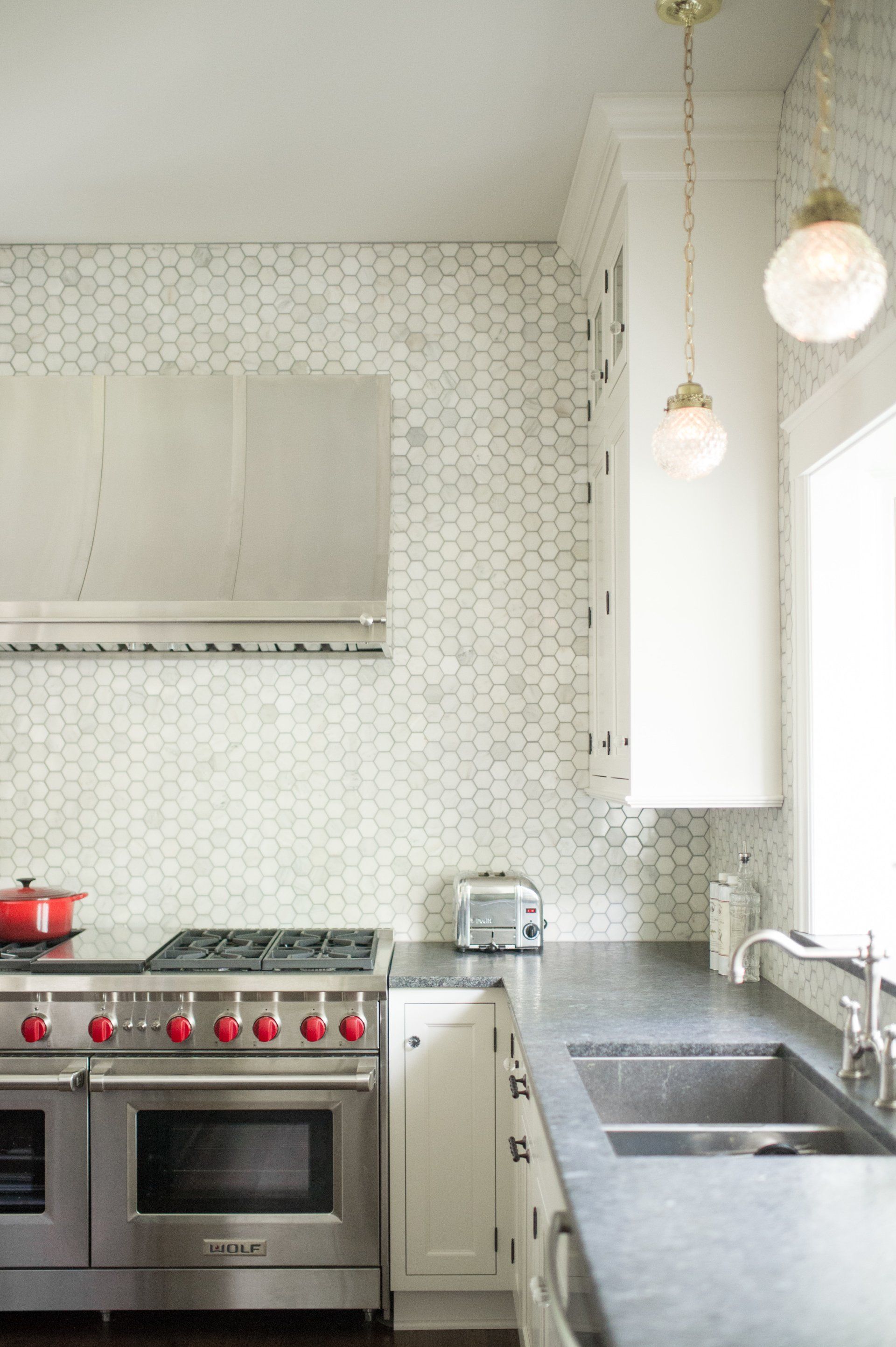 A kitchen with stainless steel appliances , white cabinets , a sink and a stove.