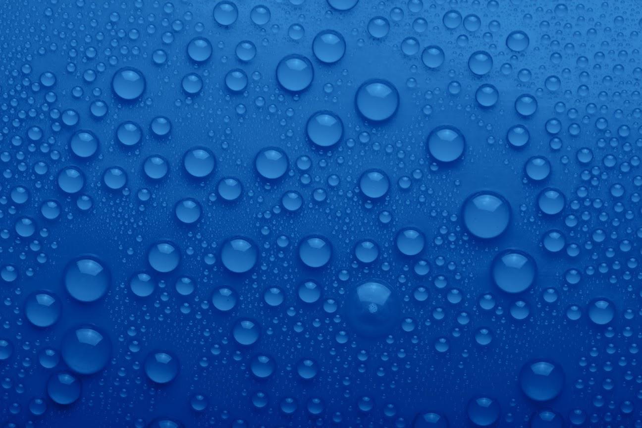 A close up of water drops on a blue surface.