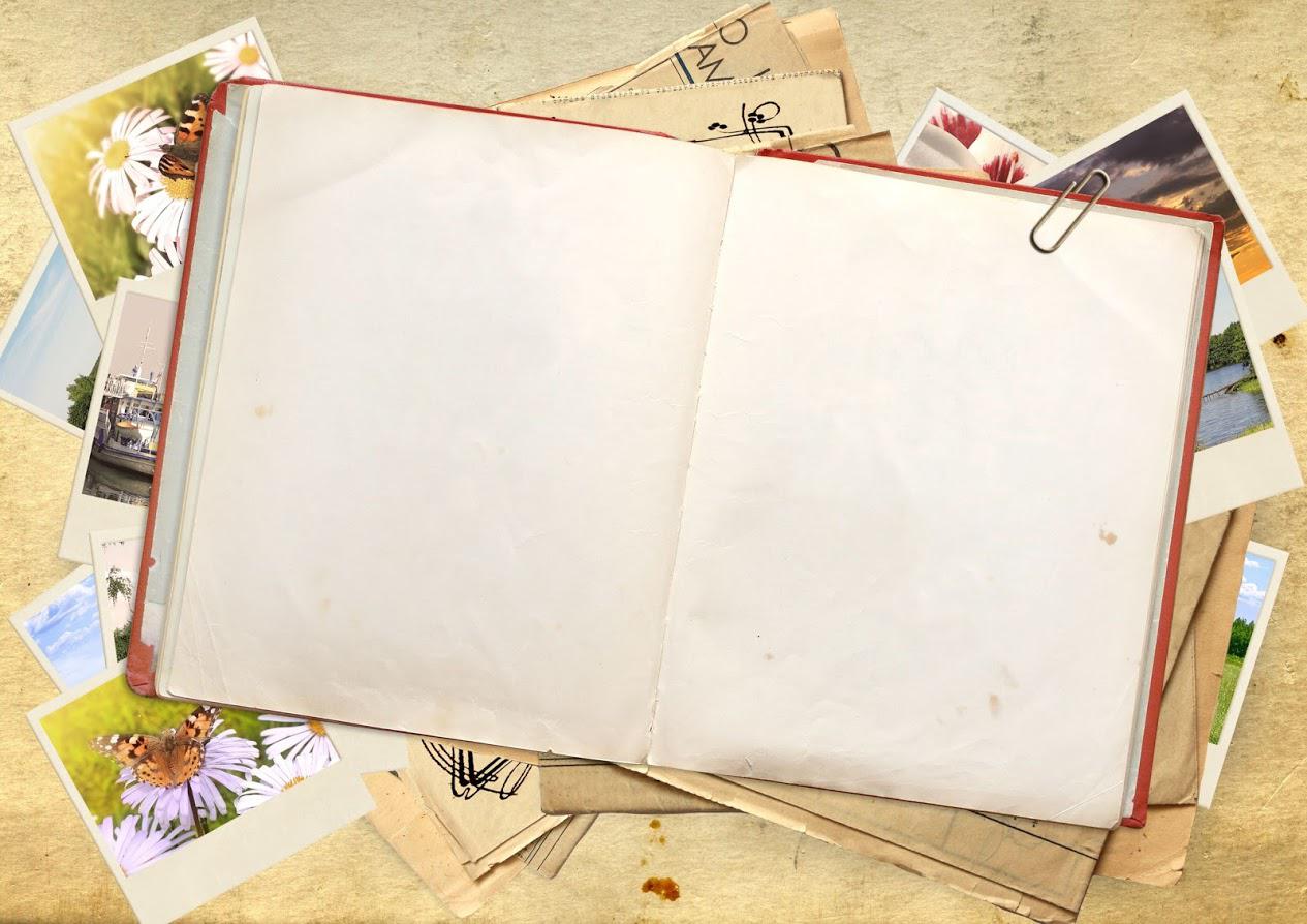 An open book is sitting on top of a pile of pictures.