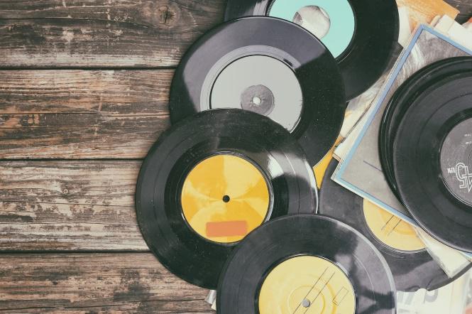 A bunch of vinyl records are stacked on top of each other on a wooden table.
