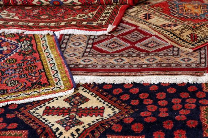 A bunch of rugs are stacked on top of each other on a table.