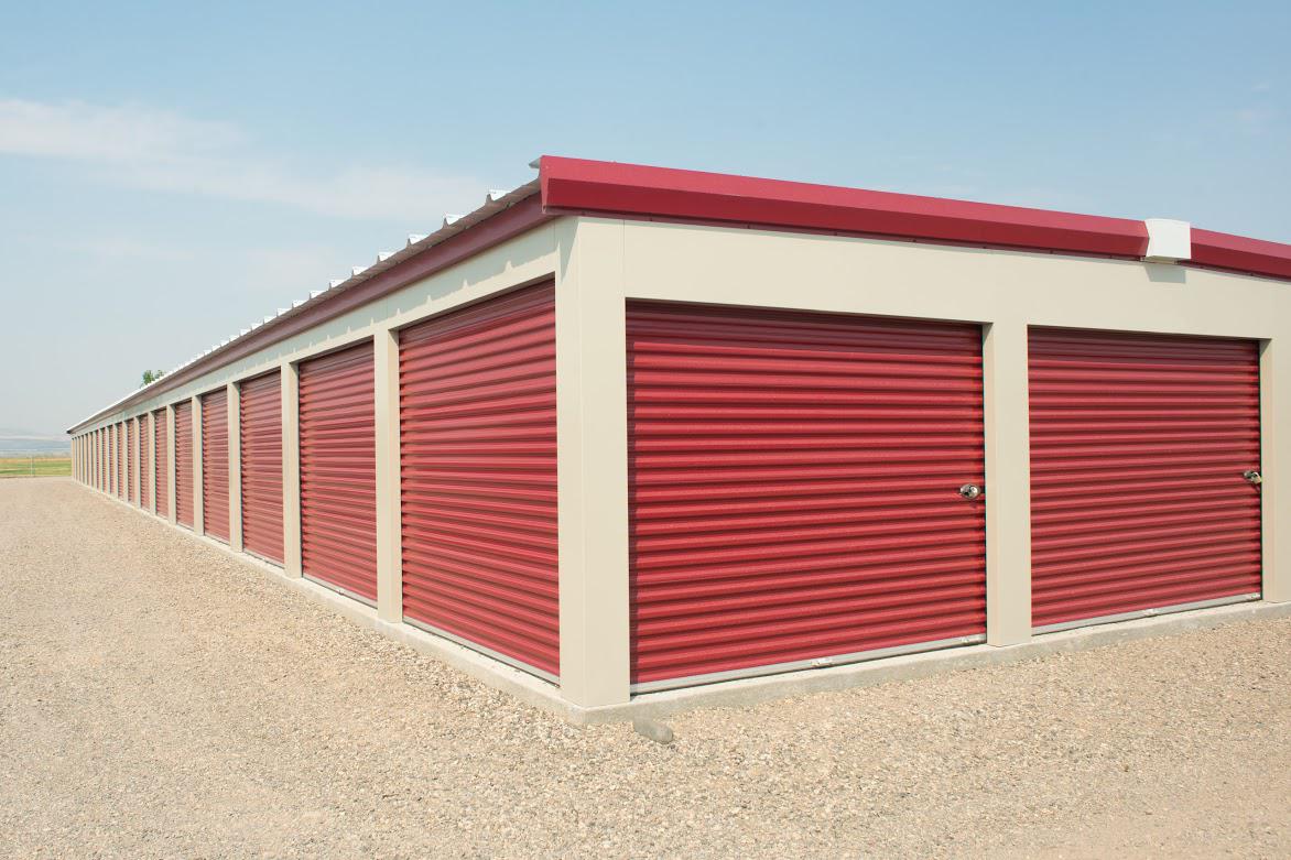 A row of red garage doors are lined up in a parking lot.