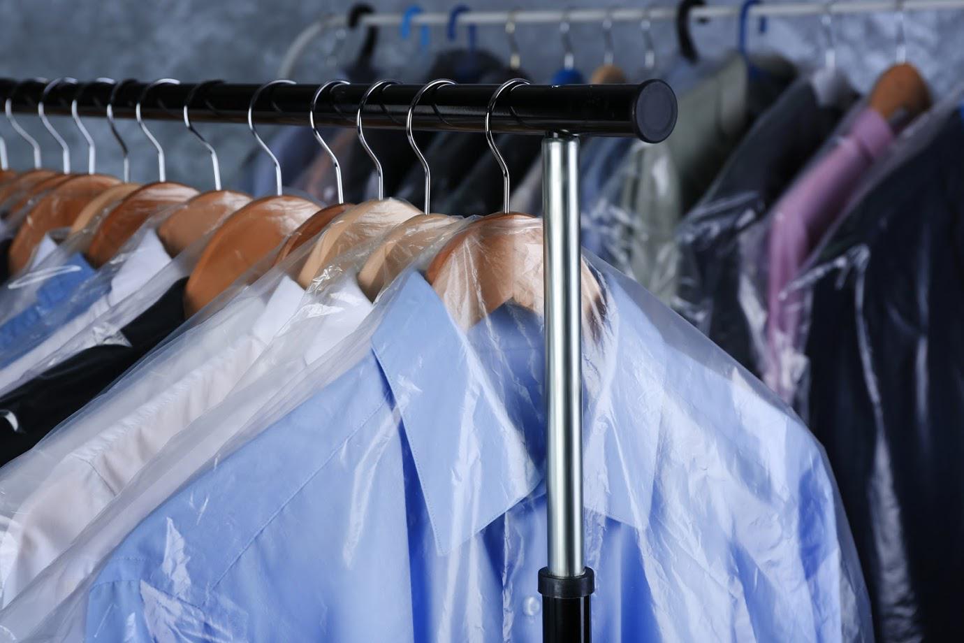 A row of shirts hanging on a rack in plastic bags