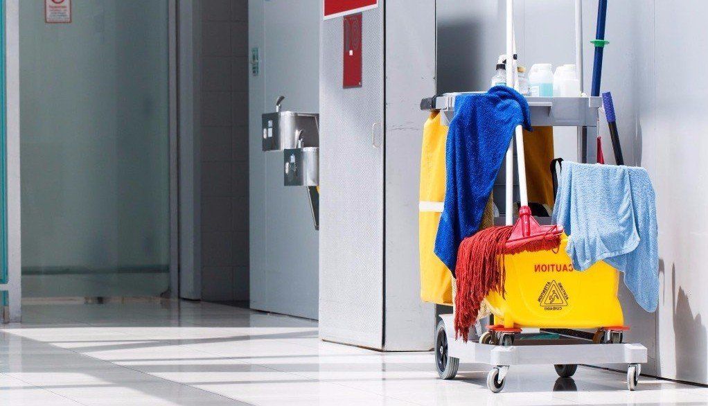 A cleaning cart with mop and towels in a hallway.